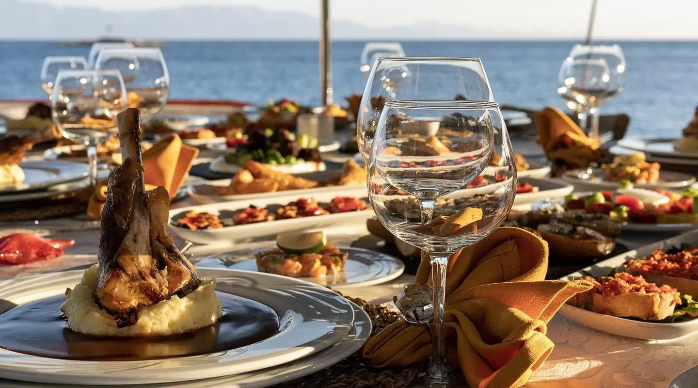 Arif Kaptan A dining deck with wine glasses and plated gourmet dishes on a seaside table