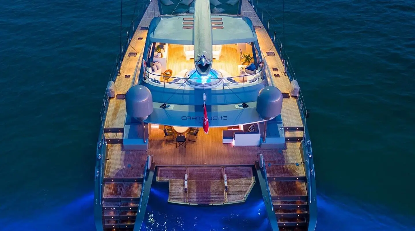 Aerial view of a luxury yacht Cartouche anchored at sunset, golden water glow