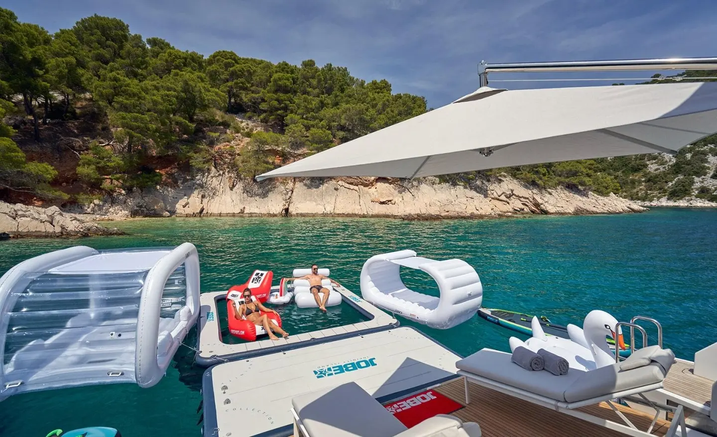 Yacht Aluminia Too docked near clear turquoise water with sunshade and seating