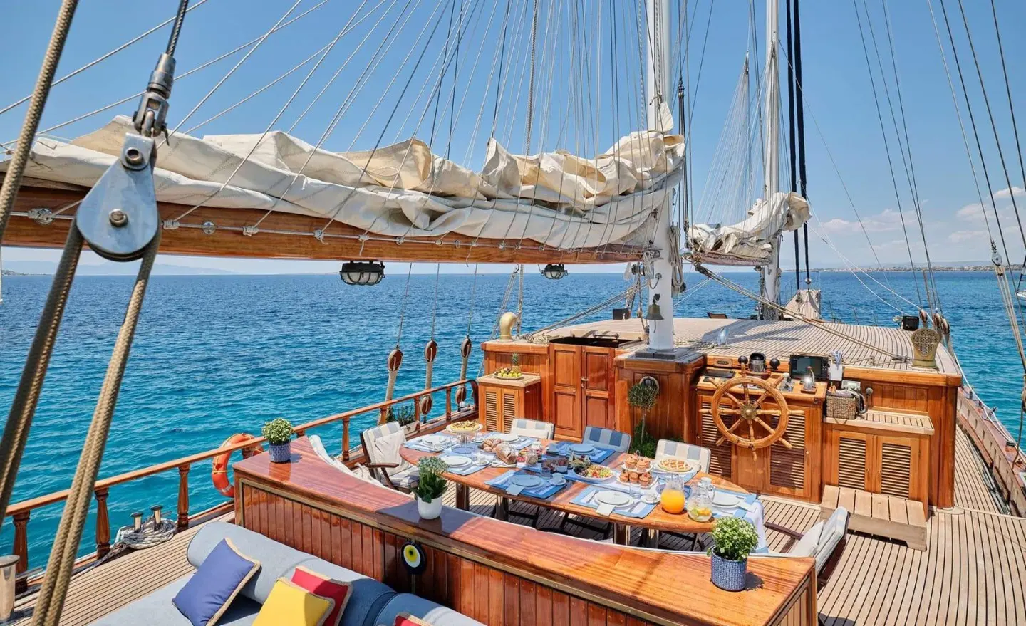 Deck scene of Gulet Myra with seating, tableware, and blue sea backdrop
