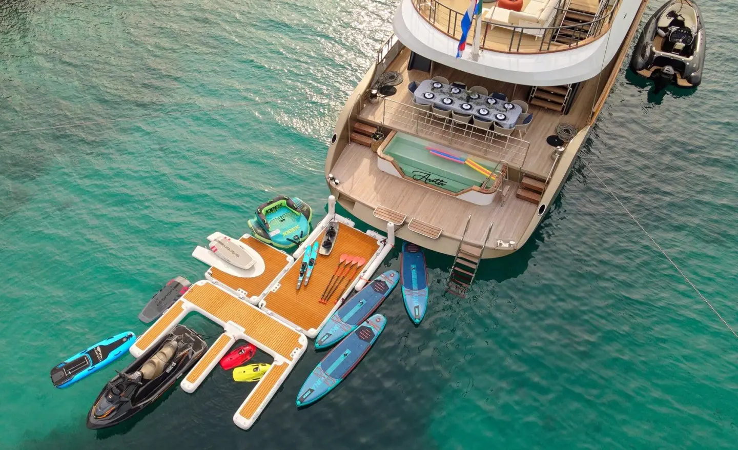 aerial view of Anetta yacht docked with small boats tied nearby in clear blue water