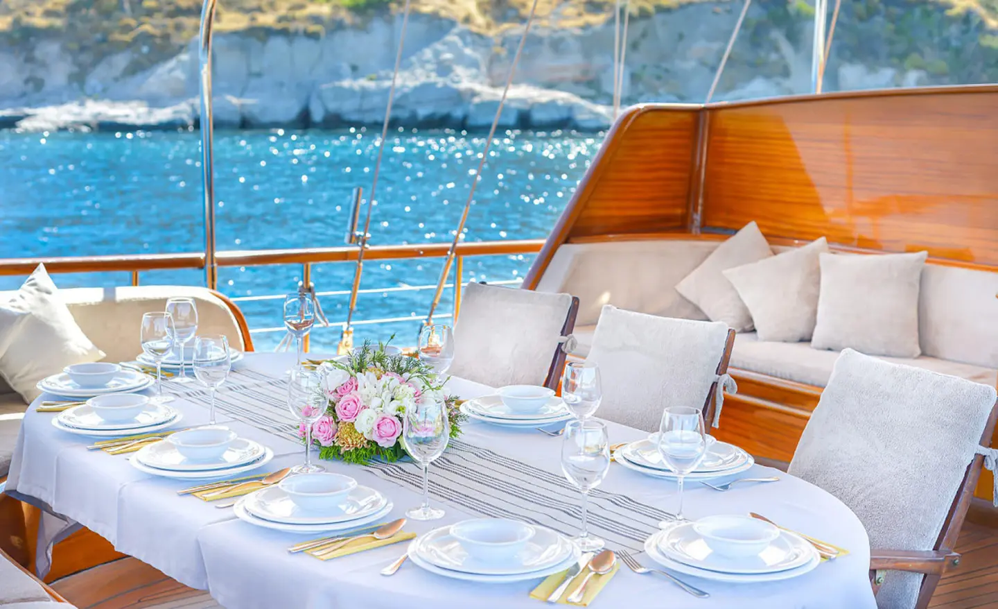 Lady Christa yacht deck dining setup with elegant tableware and pink floral centerpiece
