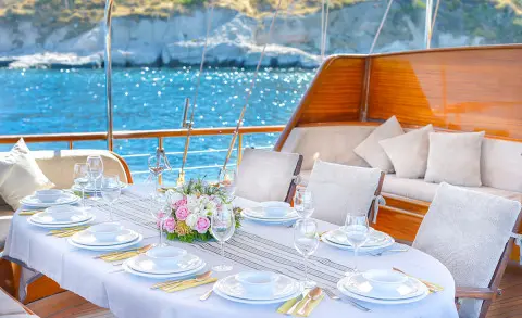 Lady Christa yacht deck dining setup with elegant tableware and pink floral centerpiece