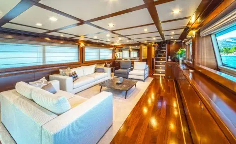 Seventh Sense luxury yacht salon bathed in sunset light with white seating and polished wooden flooring
