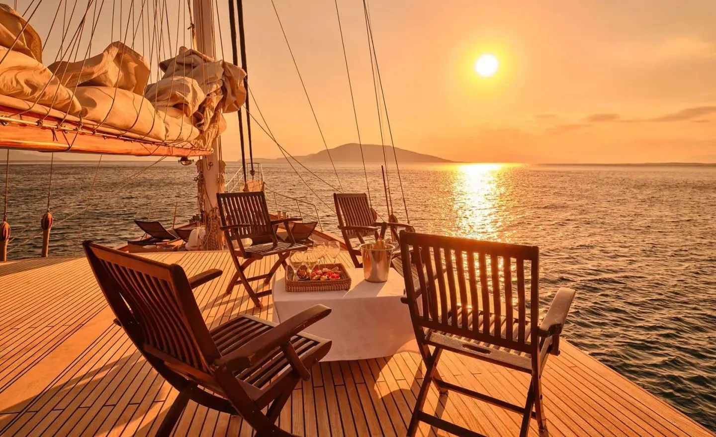 Sunset on deck of Myra yacht with lounge chairs, railing, and calm sea