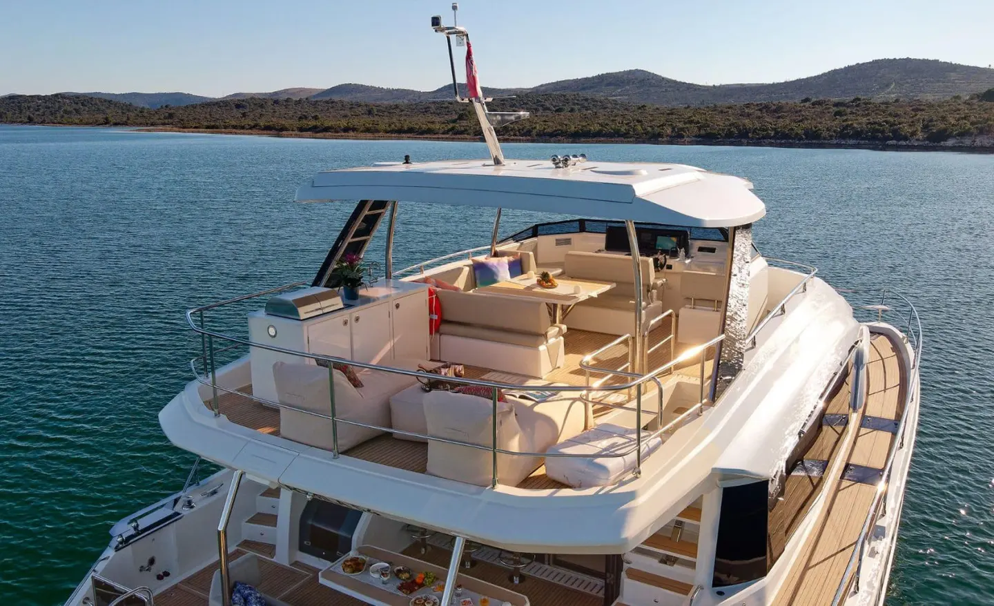 Luxurious motor yacht with open seating on upper deck photographed in sunny water