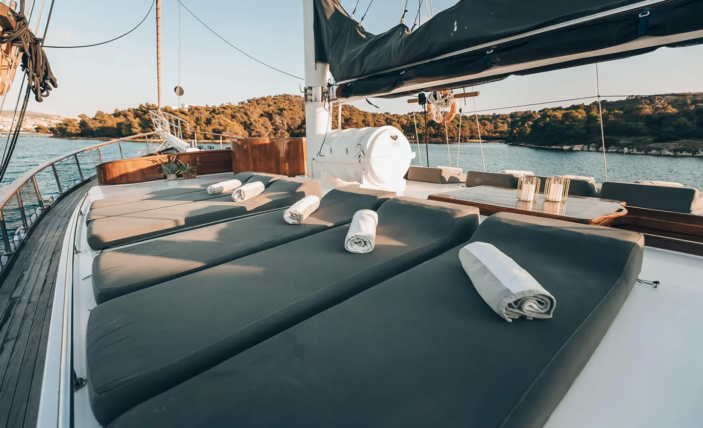 Sunset view from a luxury gulet with dark sunbeds and rolled towels