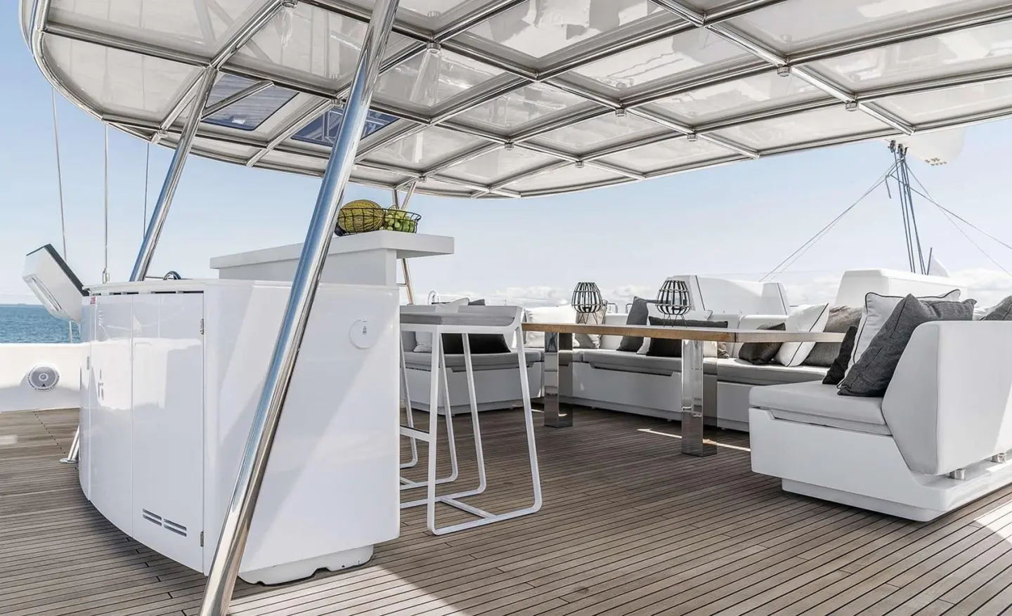White on-deck seating area with a table, shade structure overhead, and sea view