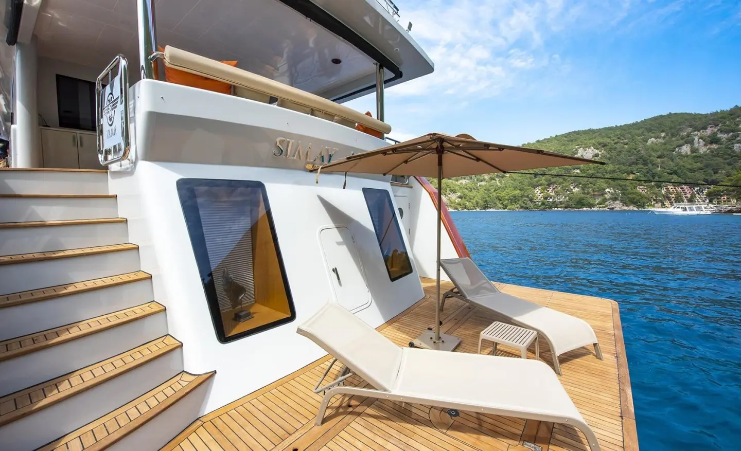 Sunlit yacht deck with lounge chairs overlooking calm azure water