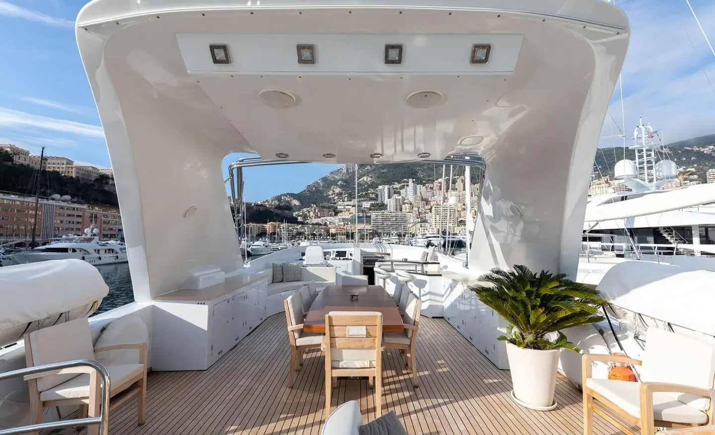 View from the yacht Brooklyn deck showing seating area, table, stairs, and potted plants