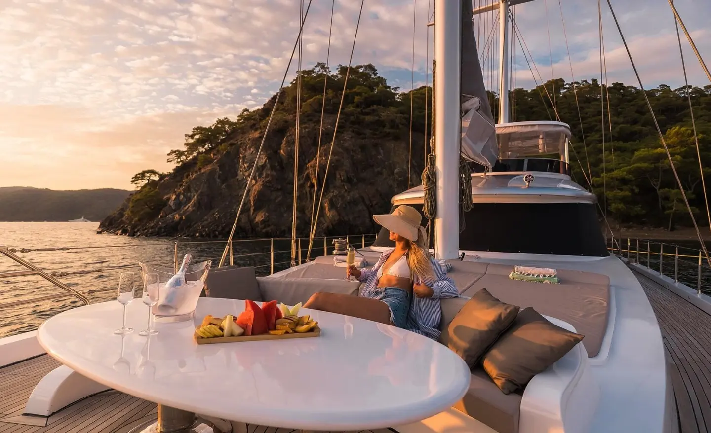 Yacht Angelo III docked at sunset with a round table and fruit platter on deck
