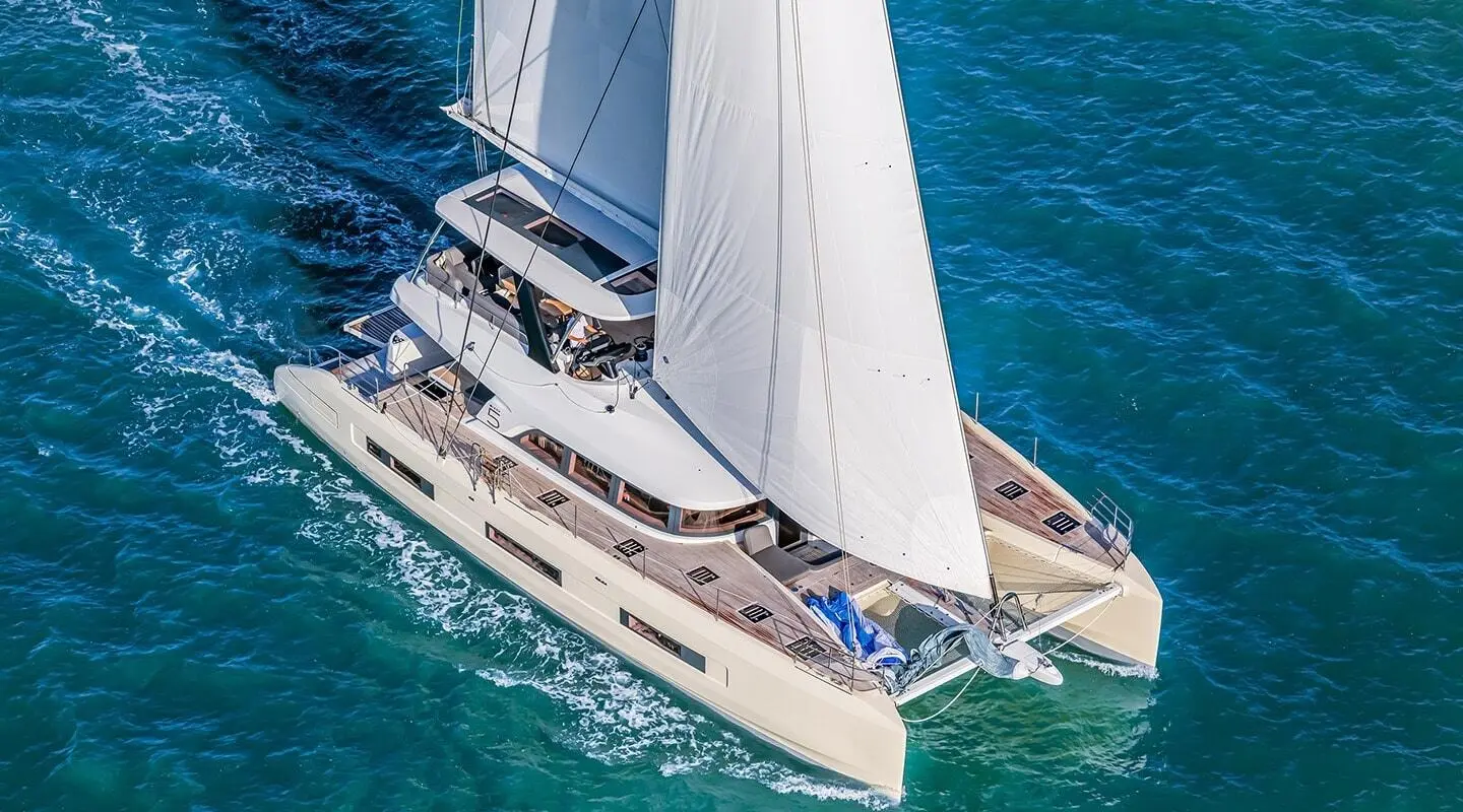 Aerial view of a white motor yacht named Daiquiri sailing blue-green water