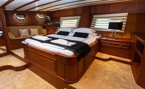 Dolce Vita yacht interior with large bed, wooden panels, and porthole windows