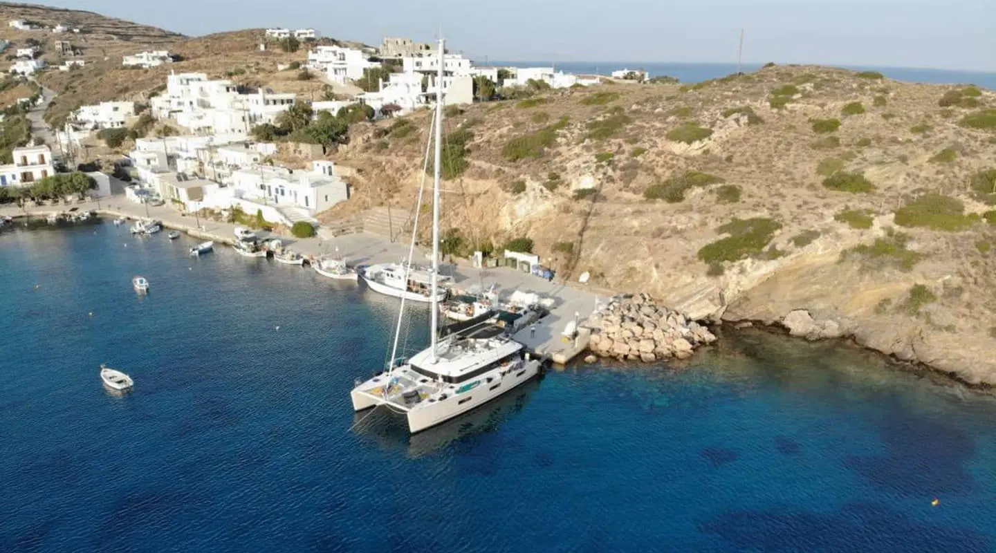 A white Atlantis motor yacht anchored near rocky coastal cliffs, blue water