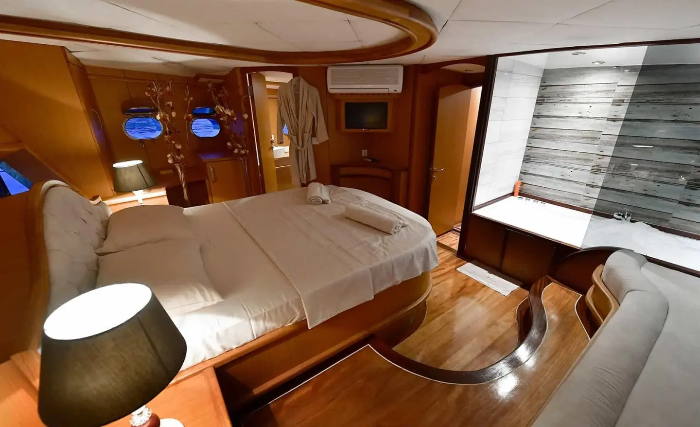 Master cabin aboard Blu Dream: wood panels, large bed, porthole window, and built-in furniture