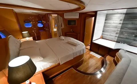 Master cabin aboard Blu Dream: wood panels, large bed, porthole window, and built-in furniture