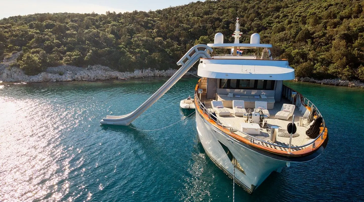 Yacht Cristal docked at sunset, sleek white hulls reflected on calm blue water
