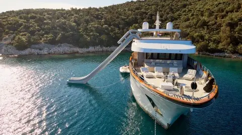 Yacht Cristal docked at sunset, sleek white hulls reflected on calm blue water