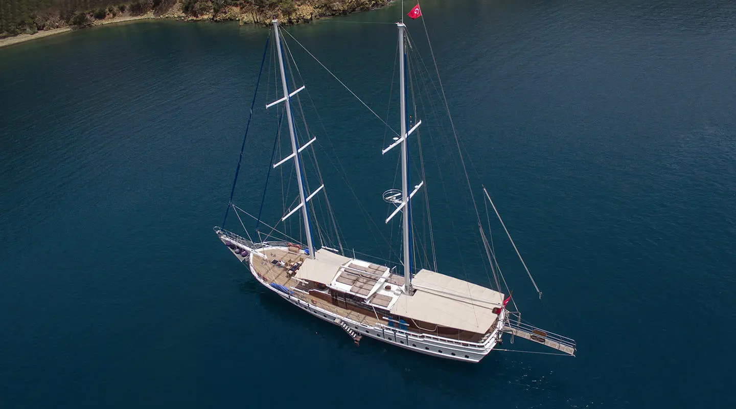 Kayhan 5 yacht anchored in calm blue water at sunset with sails stowed