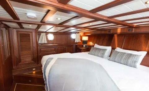Wood-paneled bedroom aboard with a double bed and grey striped pillows
