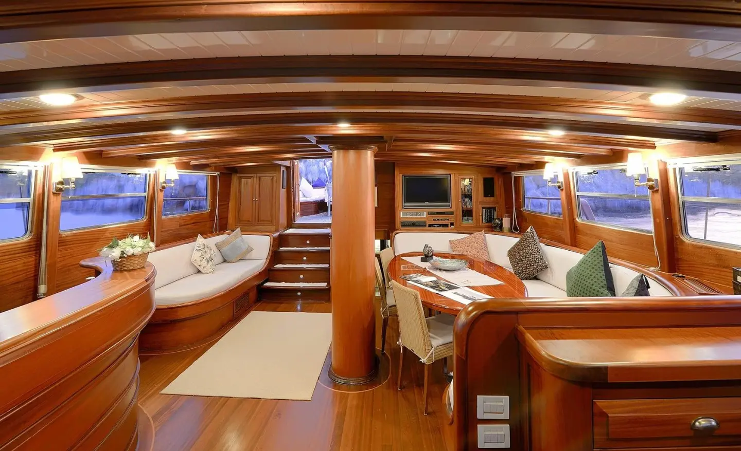 Interior of Ecce Navigo gulet saloon with wood paneling and round dining table