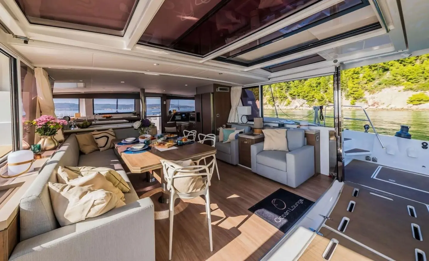 Ocean Lounge aft deck area of a motor yacht with seating and dining, sunny outdoor ambiance