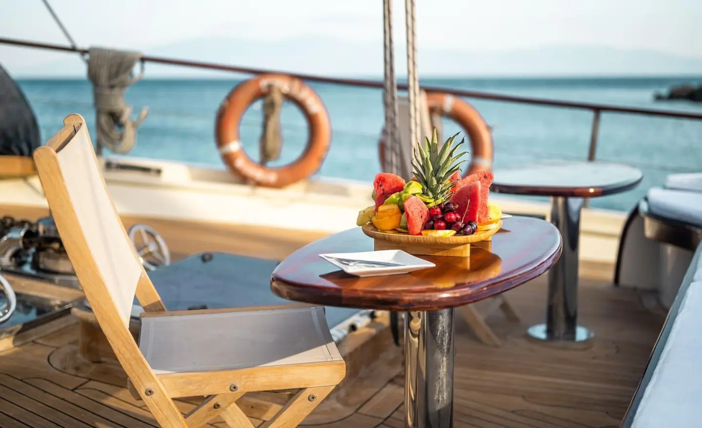 Sunset view on a luxury gulet with a round table, fruit, and lifebuoy on deck