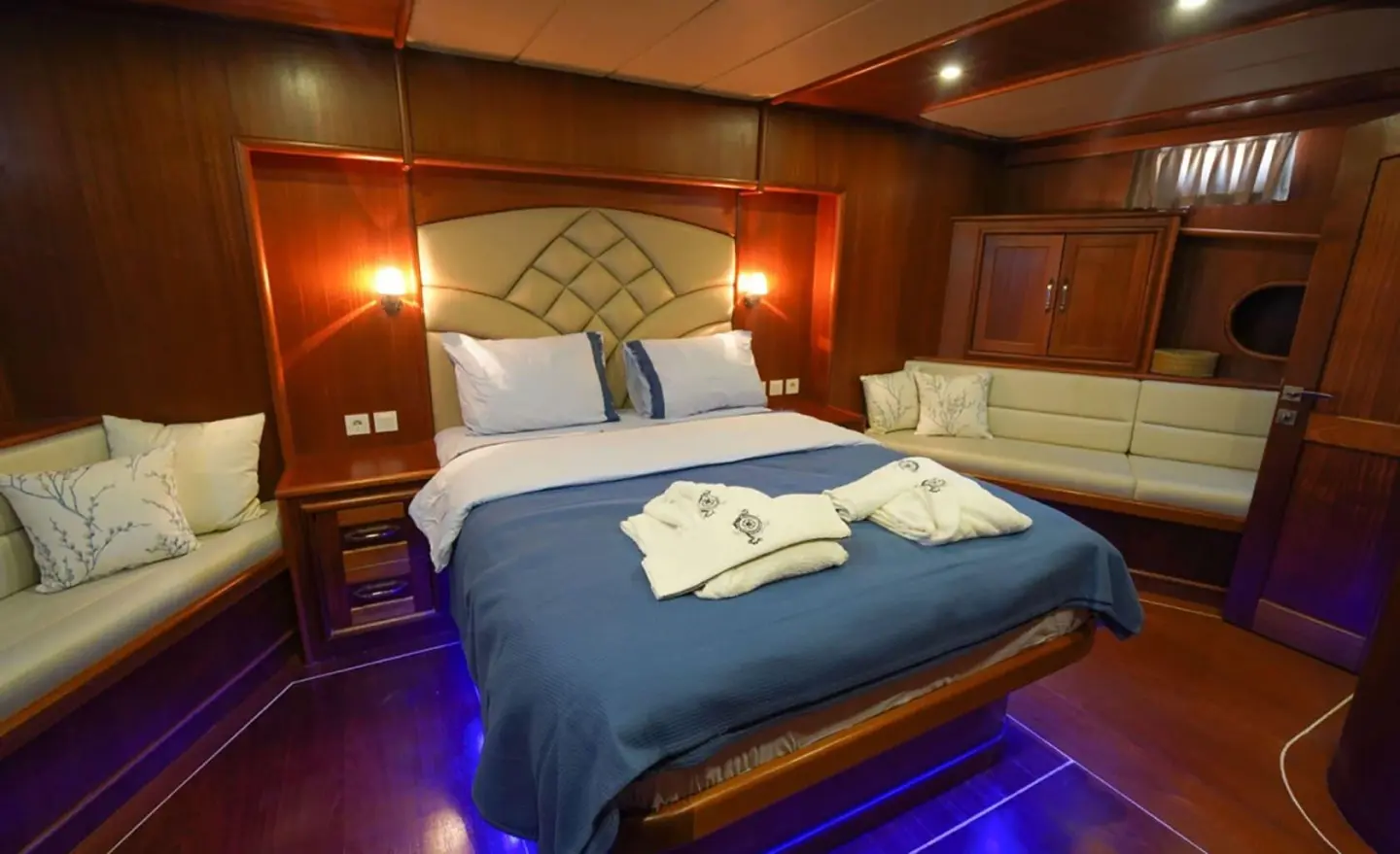 Interior cabin of Prenses Esila yacht with double bed, blue bedding, and warm lighting