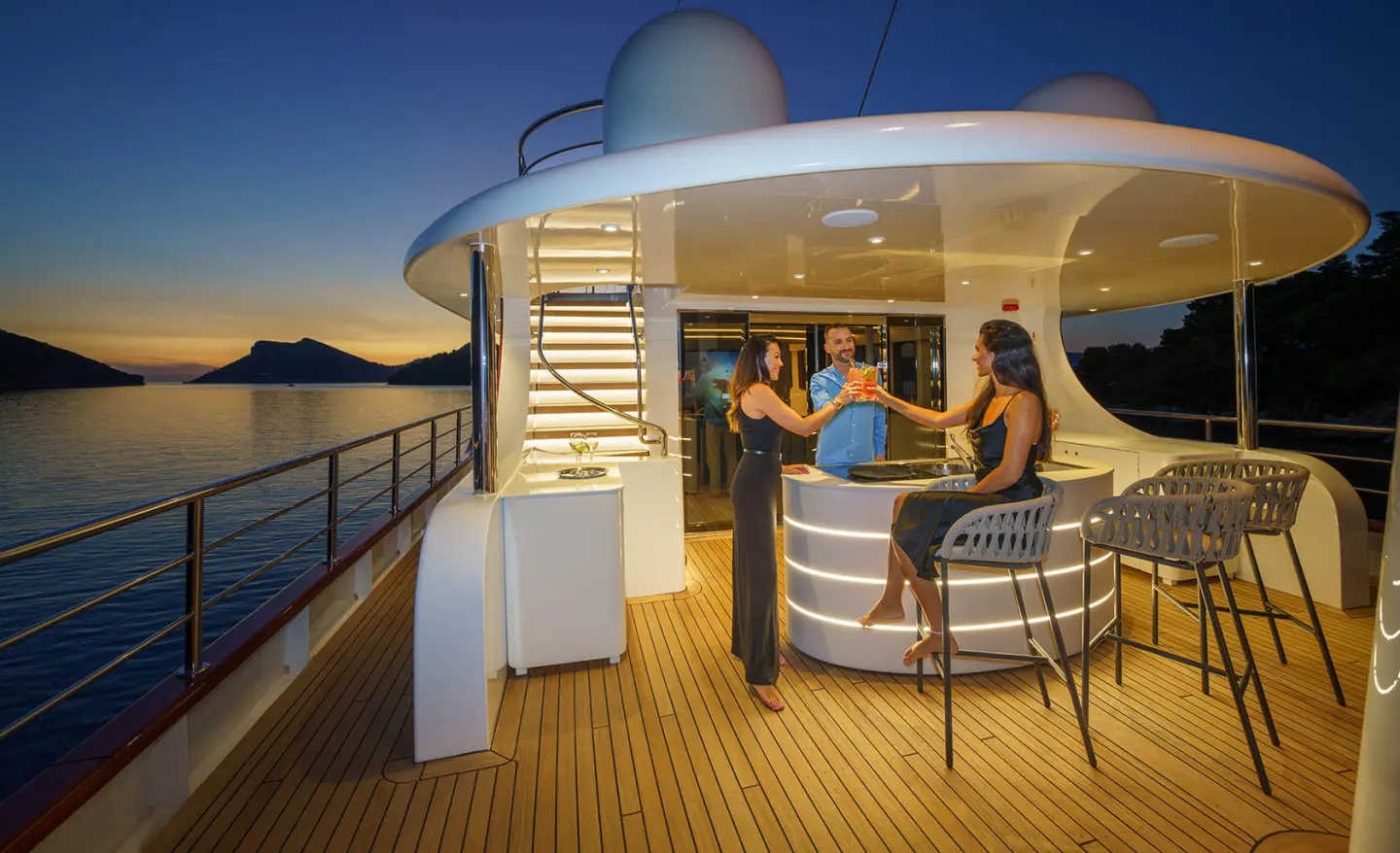 Maia luxury yacht at sunset with guests on deck near seating area