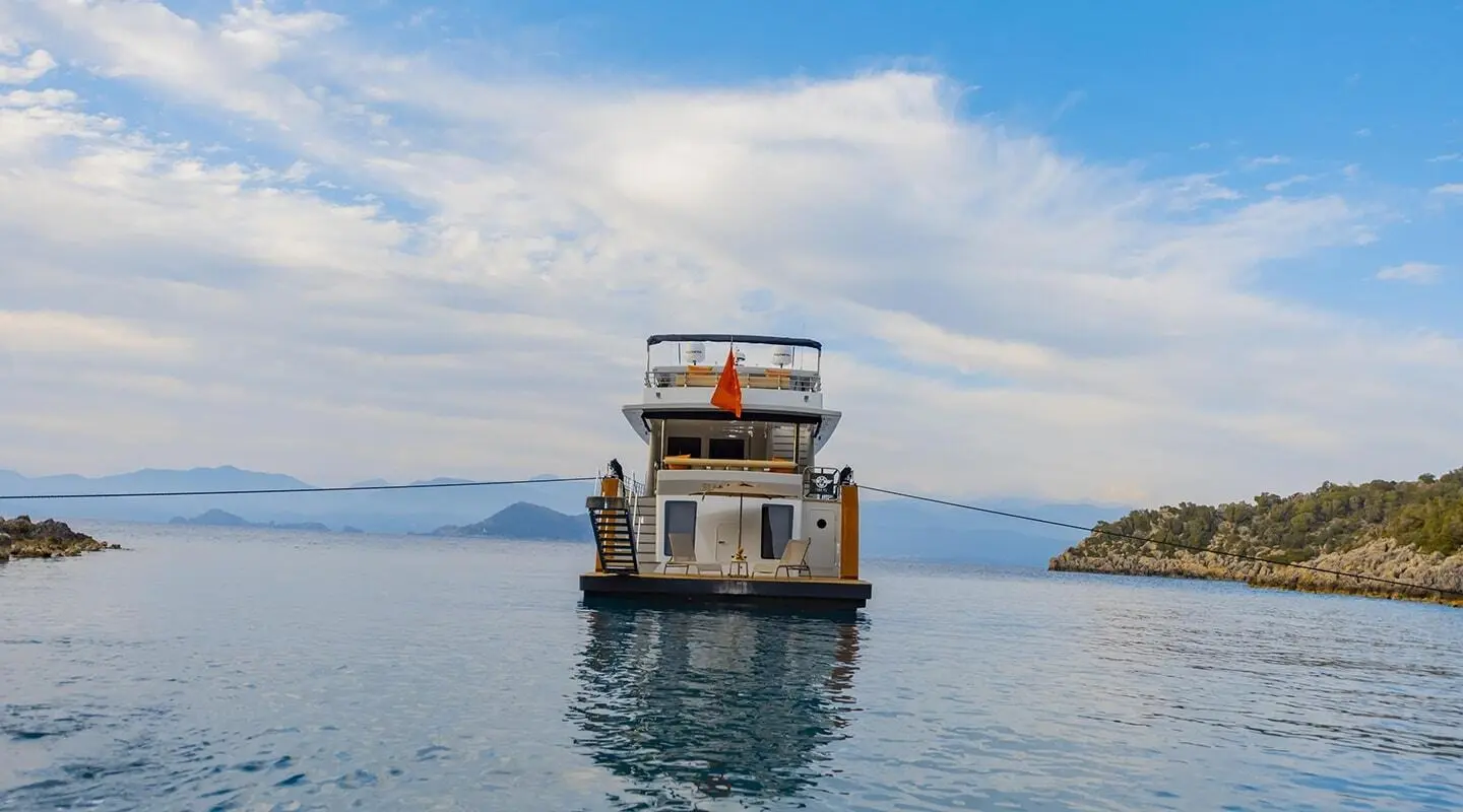 Simay M luxury yacht anchored on calm blue water at sunset harbor