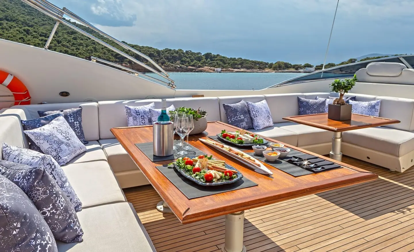 Divine motor yacht deck with sun loungers, cushions, and a plate of food aboard