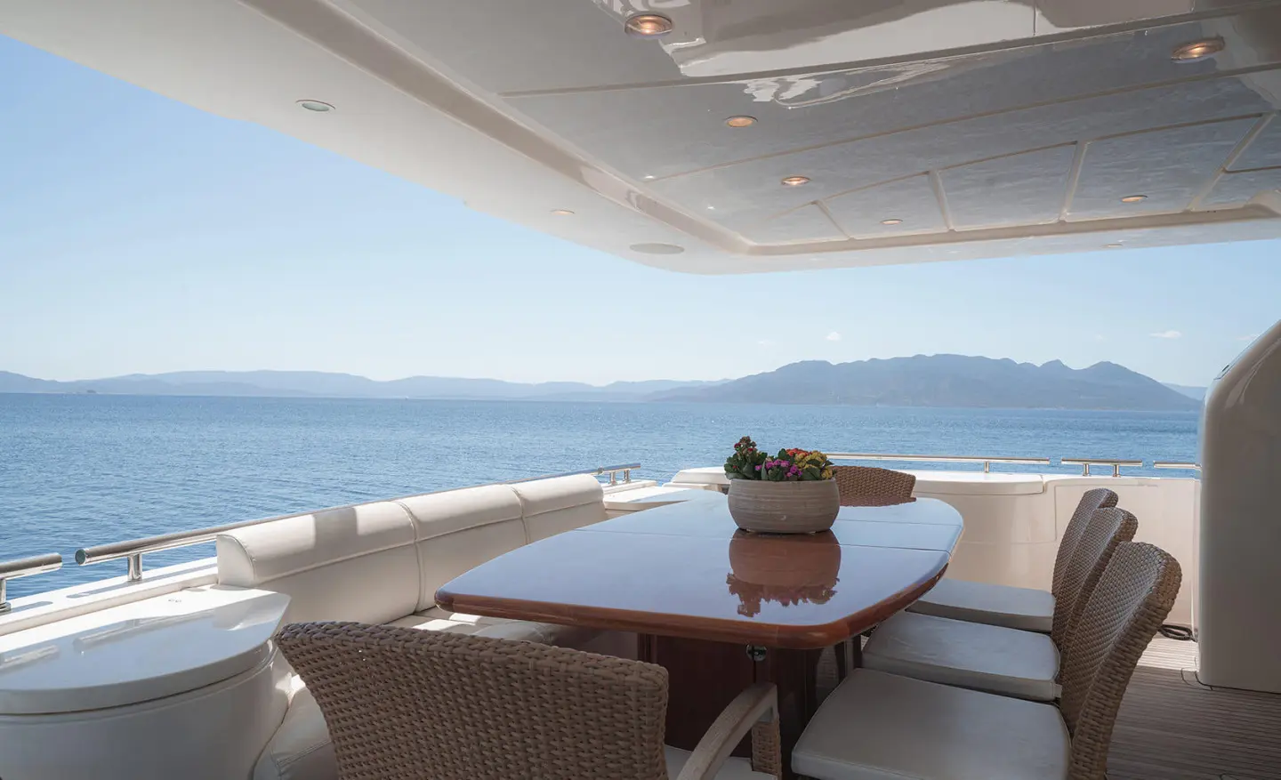 Lidia yacht dining area on deck overlooking calm sea at sunset