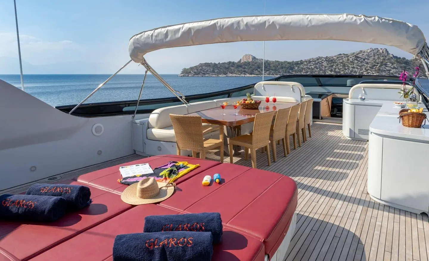 Glaros motor yacht deck seating area with red cushions and wooden table