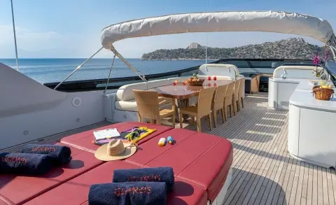 Glaros motor yacht deck seating area with red cushions and wooden table