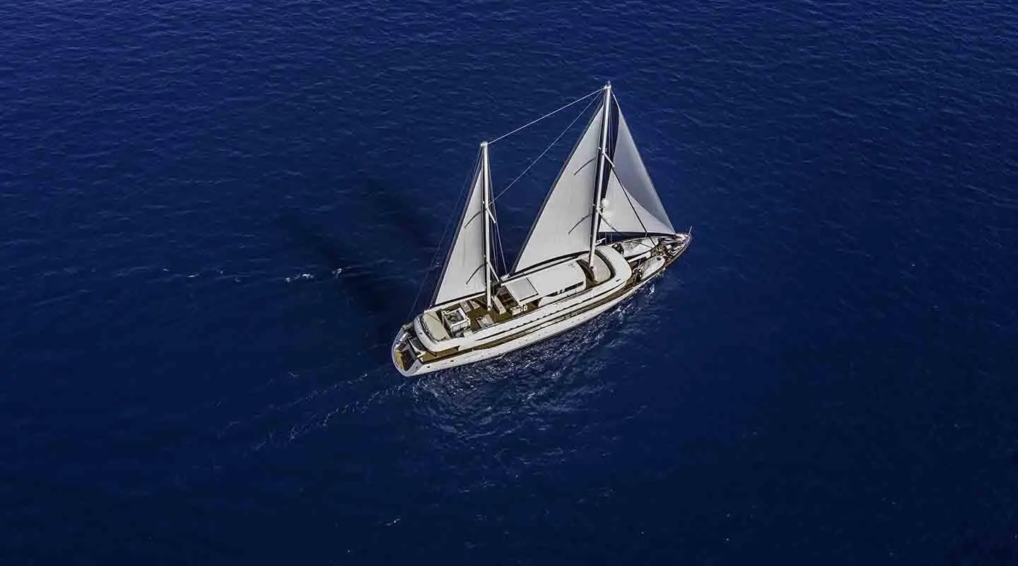 Omnia yacht with white sails on blue open sea