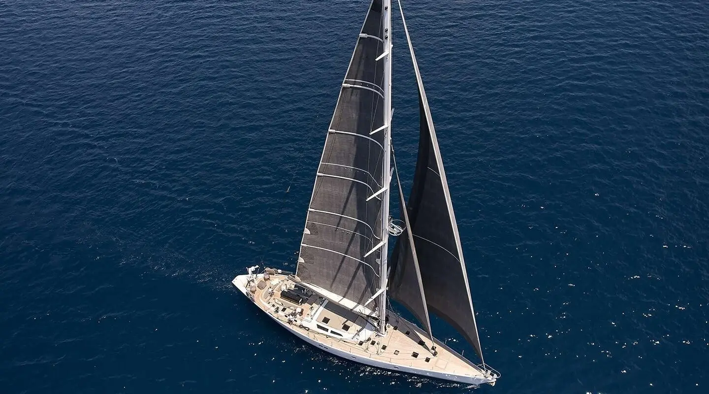 Yacht Aizu sails on calm blue sea under clear sky, viewed from above