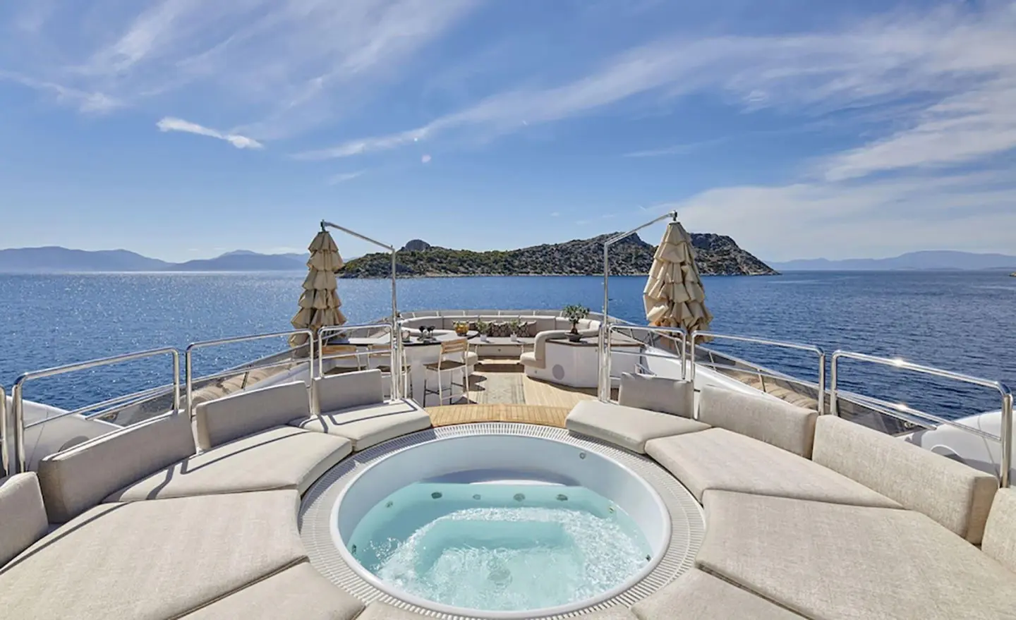 Daloli yacht deck with circular hot tub, lounge seating, and clear sea view
