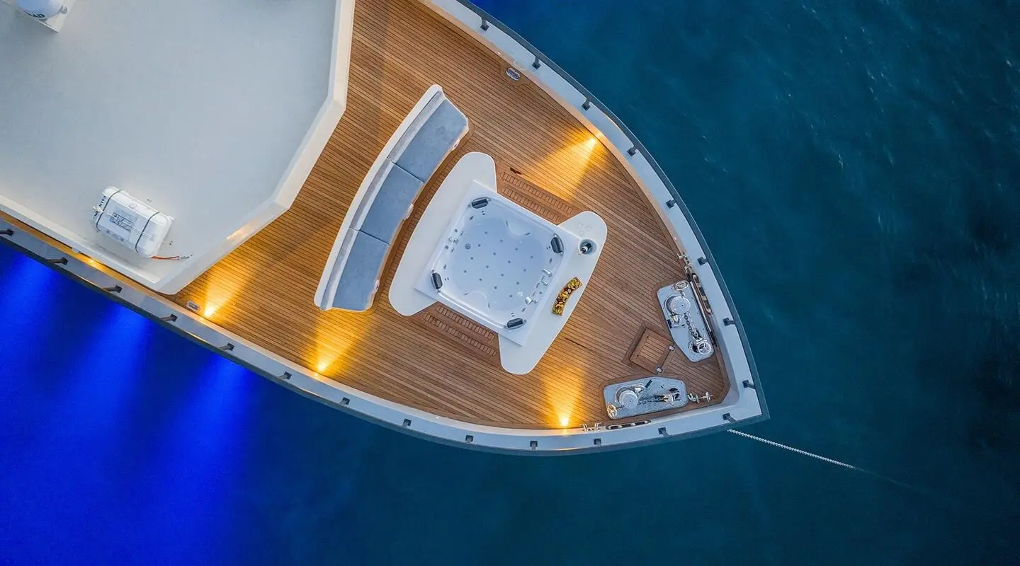 Aerial view of a yacht with a hot tub on the wooden deck and seating benches