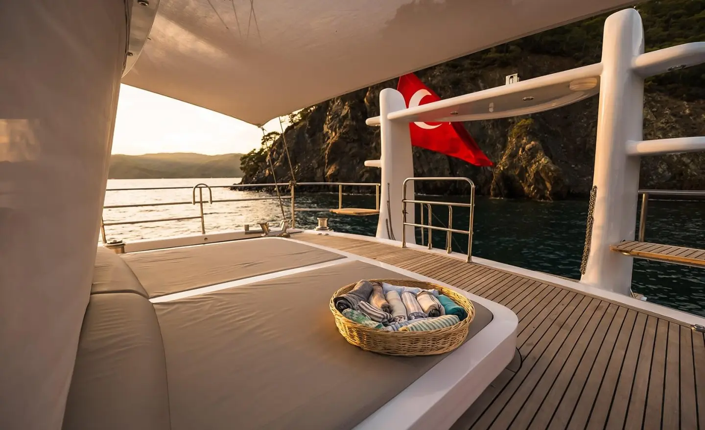 Angelo III yacht deck at sunset with small boat, seats, railing, and water