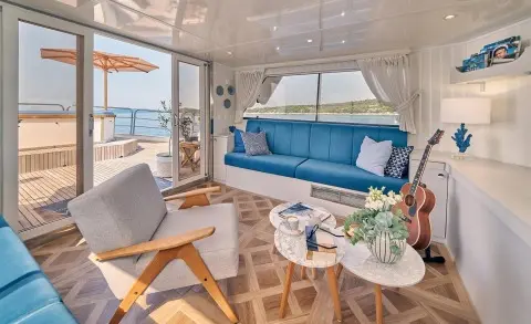 La Perla yacht lounge area with blue cushions, white seating, and wooden table