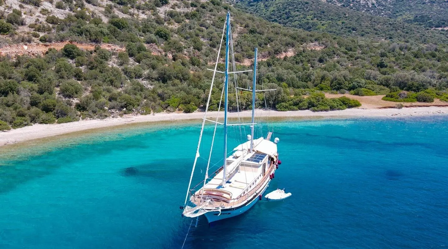 Ulucinar gulet anchored in turquoise bay with coastline