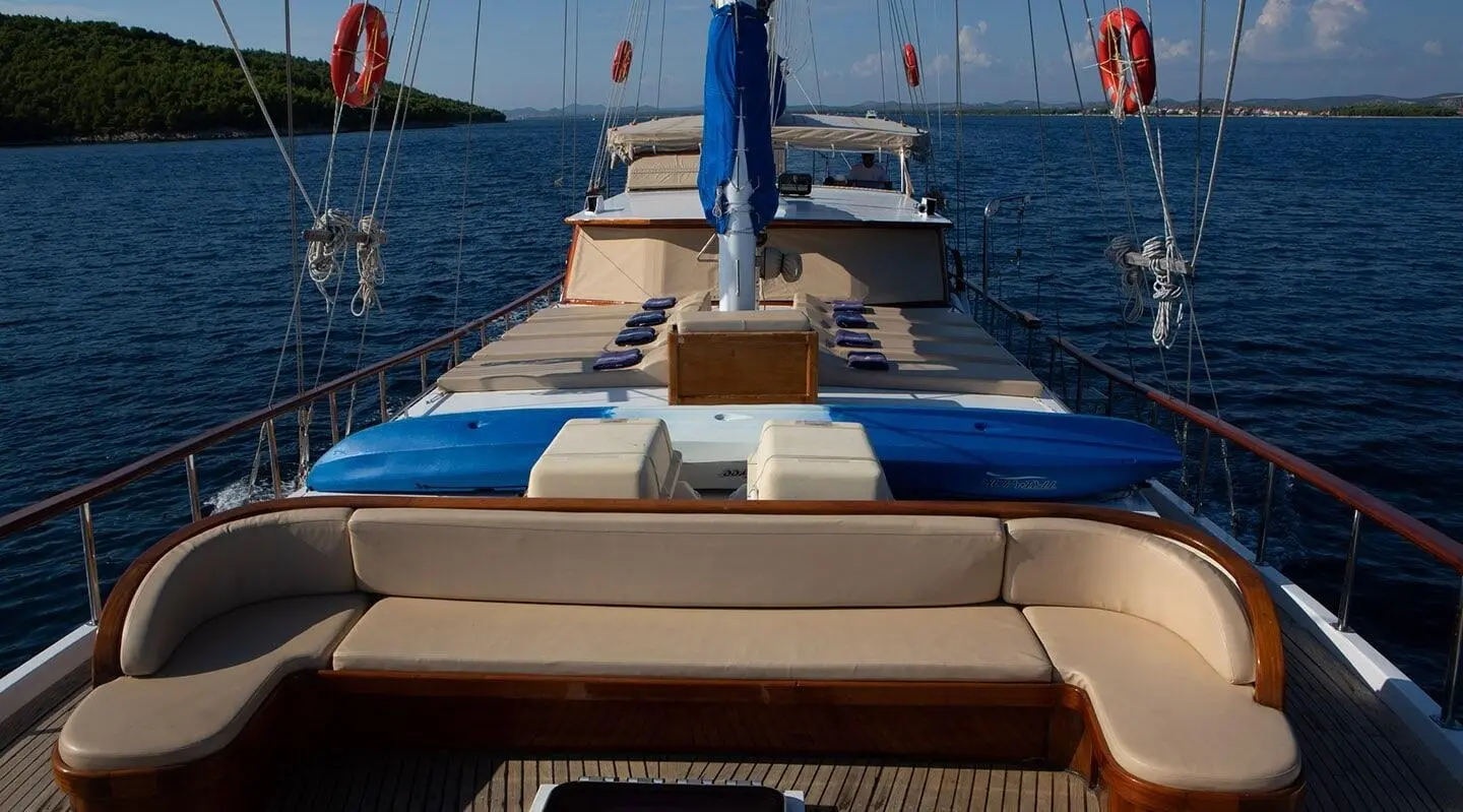 Yacht Malena deck with sun loungers and blue cushions at sunset on calm sea