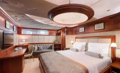 Luxurious yacht Lady Gita bedroom with polished wood cabinetry and designer bed