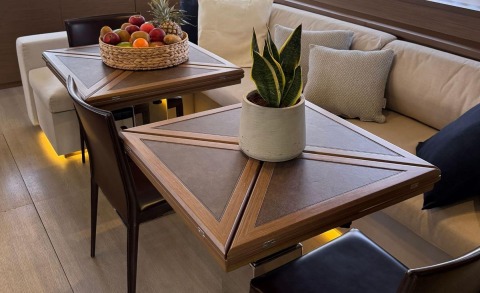 Atlantis yacht interior with a triangular wooden table, fruit basket, and a potted plant