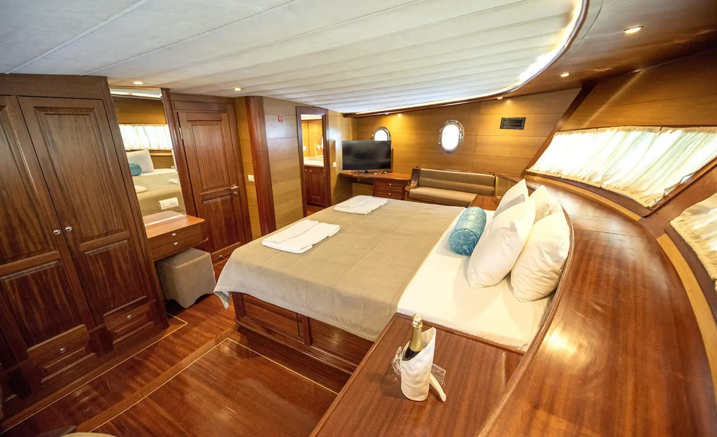 Kayhan 4 yacht interior with wooden panels, two beds, cushions, and warm lighting