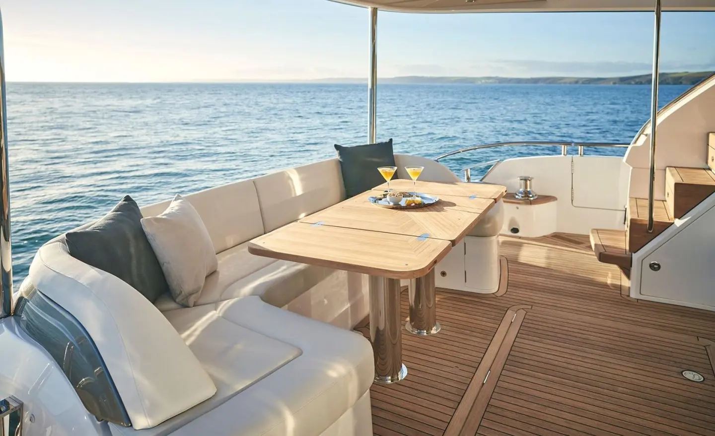 Elizabeth yacht deck with seating area, wooden table, sun cushions, and sea view