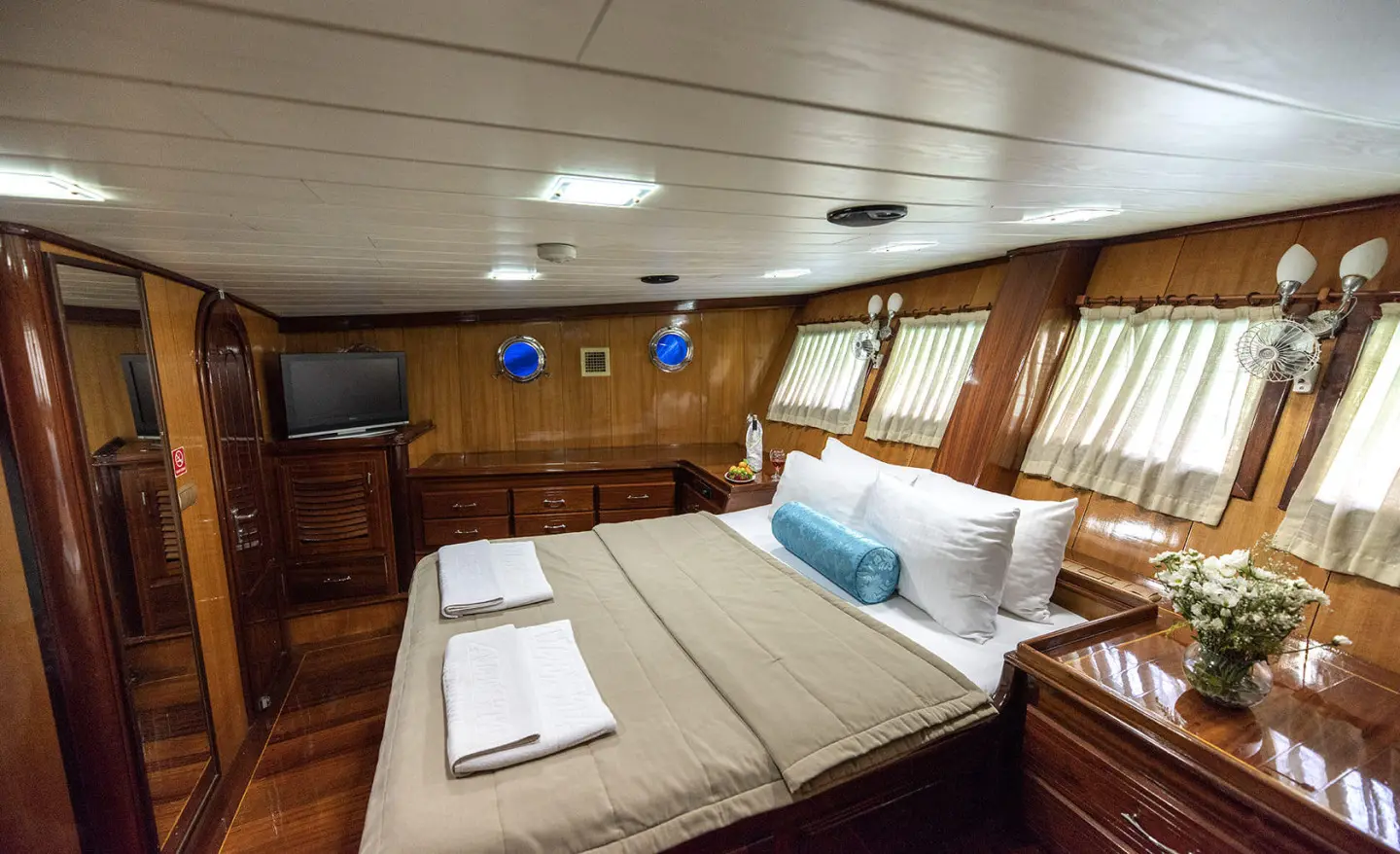 Kayhan 8 yacht interior bedroom with bed, pillows, wooden cabinetry, and windows