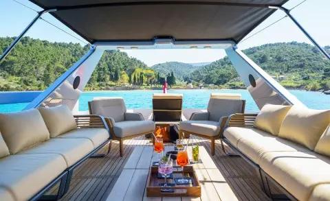 Phantom yacht aft deck scene with seating, table, and view of sea and coastline