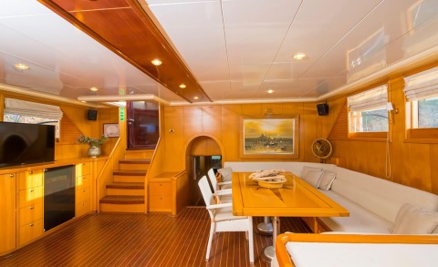 Interior of a luxury yacht with wooden panels, dining table and seating area
