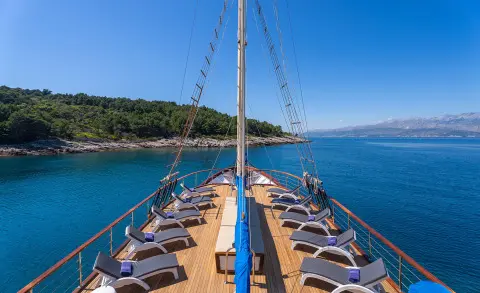 View along the wooden deck toward the bow of Mendula yacht at sea during calm blue hour